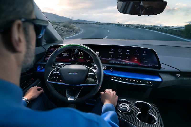 Front View of the 2026 OPTIQ-V Driving Through the Dusk Utilizing its Headlights | McLaughlin Cadillac in Moline IL