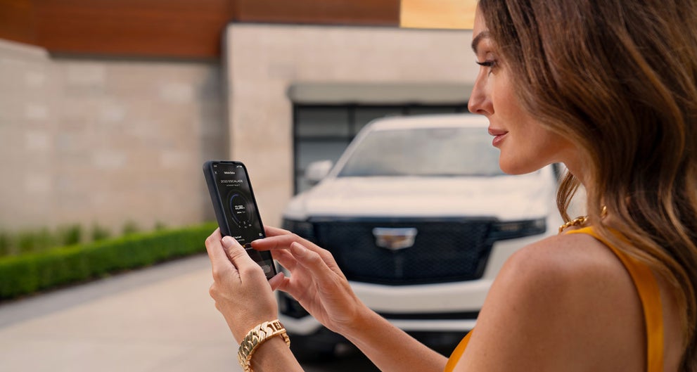 lady checking her mobile with a Cadillac vehicle background | McLaughlin Cadillac in Moline IL